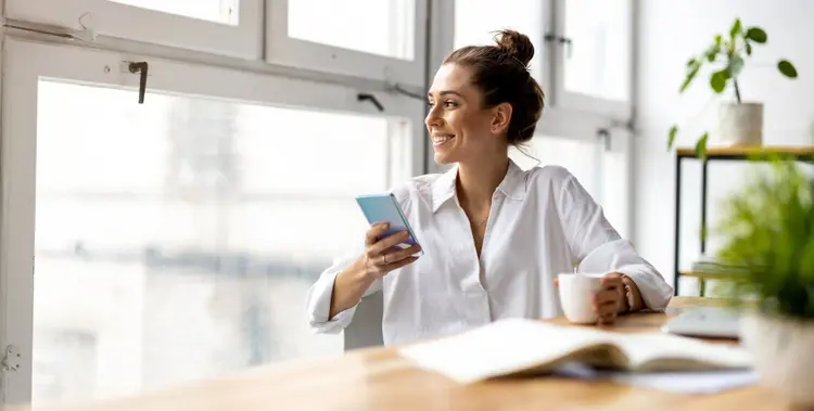 frau-mit-handy-am-tisch-blick-nach-draußen